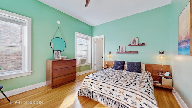 bedroom with cooling unit, baseboards, and wood finished floors