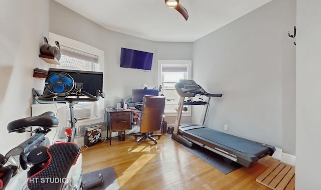 workout area with wood finished floors, a ceiling fan, and baseboards