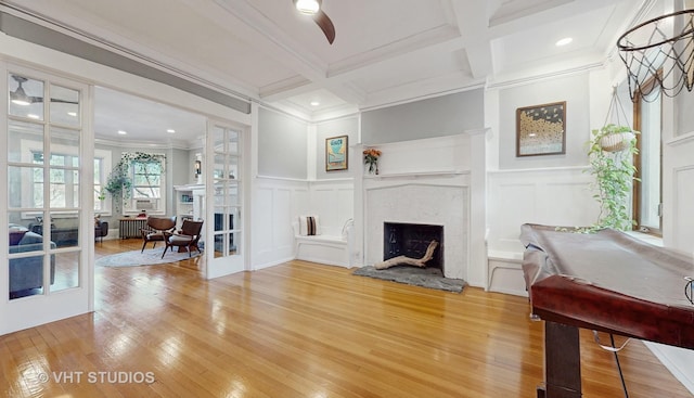 living room with french doors, a fireplace, a decorative wall, and beam ceiling