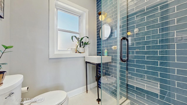 bathroom with baseboards, a shower stall, and toilet