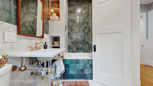 bathroom with tiled shower / bath combo, tile walls, and toilet