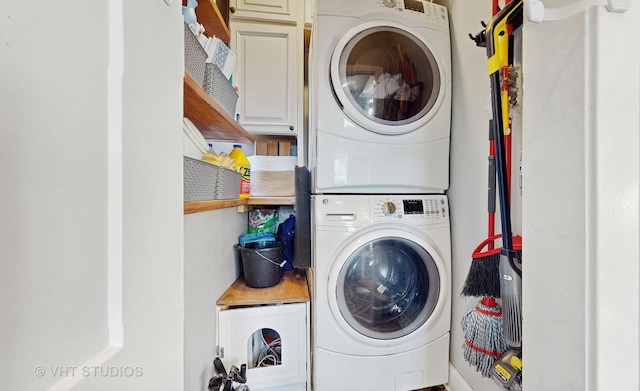 laundry area featuring stacked washer and dryer and cabinet space