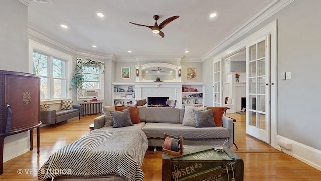 living room featuring ornamental molding, radiator, a large fireplace, and light wood finished floors