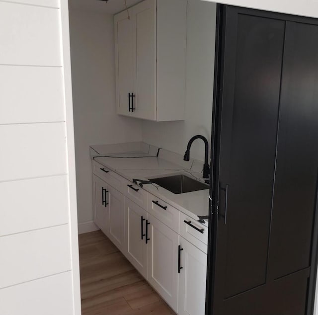 kitchen with white cabinetry, sink, and light hardwood / wood-style floors