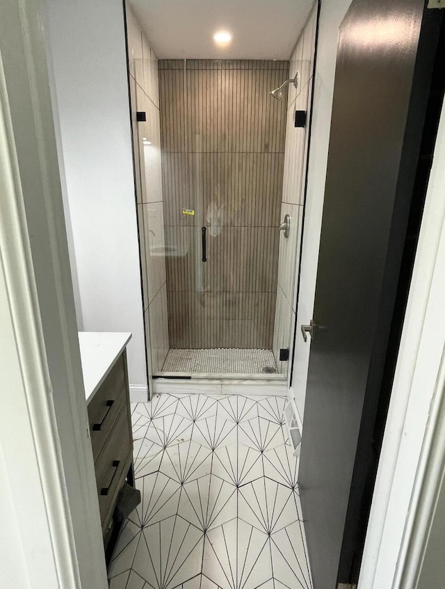 bathroom with an enclosed shower, vanity, and tile patterned flooring