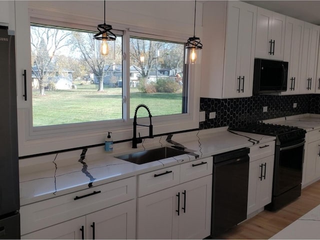 kitchen featuring decorative light fixtures, sink, white cabinets, and black appliances