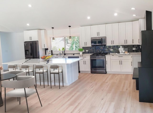 kitchen with appliances with stainless steel finishes, a breakfast bar, pendant lighting, and white cabinets