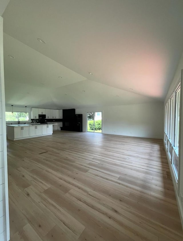 unfurnished living room featuring high vaulted ceiling and light wood-type flooring