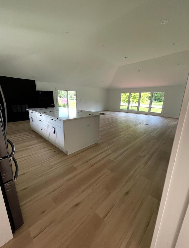 kitchen featuring white cabinetry, light hardwood / wood-style flooring, lofted ceiling, and a kitchen island