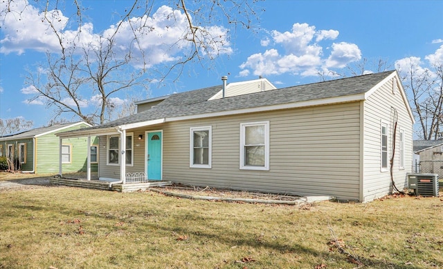 rear view of house with covered porch, central AC, and a lawn