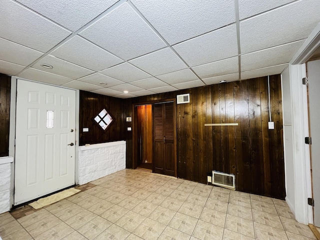 entryway with a paneled ceiling and wood walls