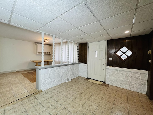 interior space featuring a drop ceiling and wooden walls