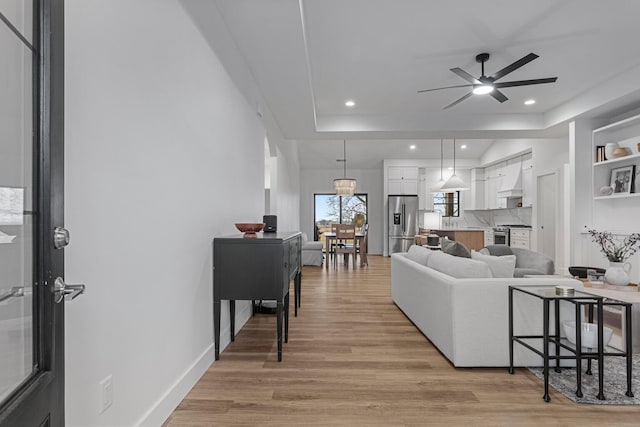 living room featuring a ceiling fan, recessed lighting, baseboards, and light wood finished floors