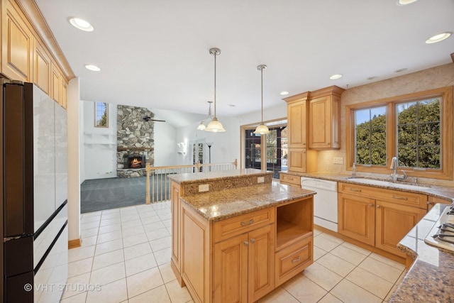 kitchen featuring pendant lighting, sink, white appliances, a fireplace, and a kitchen island