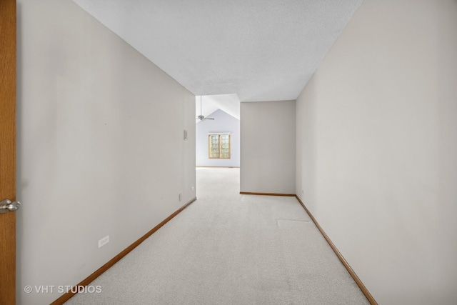 hallway featuring light colored carpet and a textured ceiling