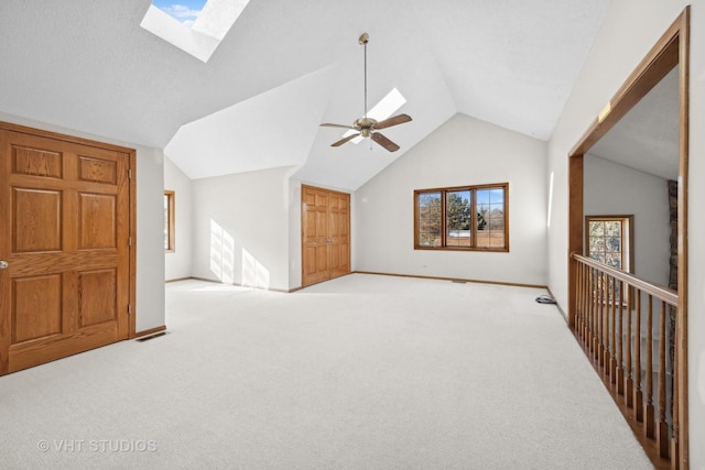 bonus room with light carpet, lofted ceiling with skylight, and ceiling fan