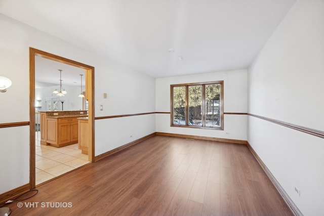 empty room with an inviting chandelier and light wood-type flooring