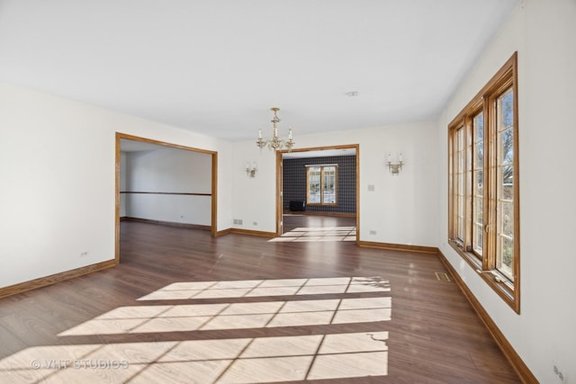 empty room featuring an inviting chandelier and dark hardwood / wood-style floors