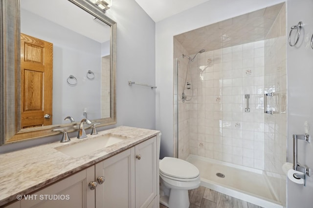 bathroom with hardwood / wood-style floors, vanity, a tile shower, and toilet