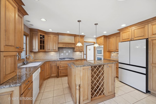 kitchen with sink, white appliances, a center island, stone countertops, and decorative light fixtures