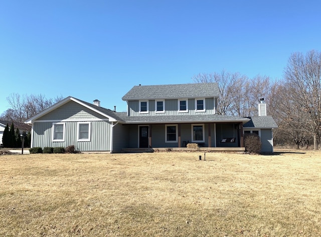 view of front of home featuring a porch, a chimney, a front yard, and a shingled roof