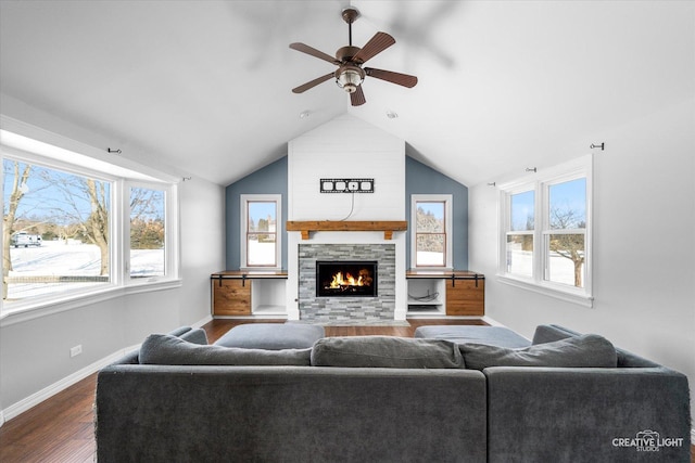 living area with a fireplace, a healthy amount of sunlight, dark wood-style flooring, and a ceiling fan