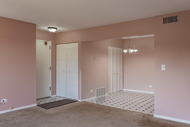 carpeted spare room featuring a notable chandelier