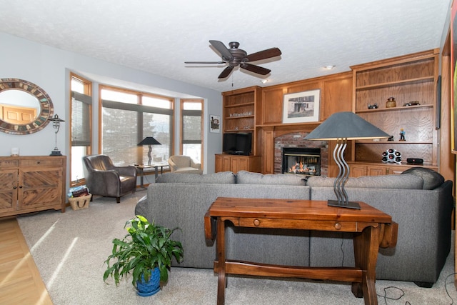 living room featuring a textured ceiling, a brick fireplace, and a ceiling fan