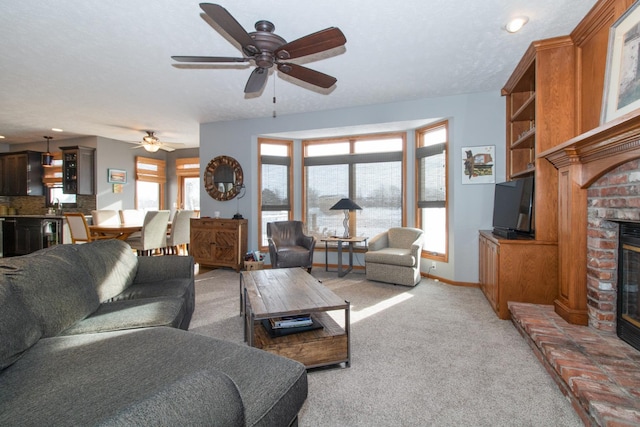 living room featuring light carpet, a brick fireplace, a ceiling fan, and baseboards