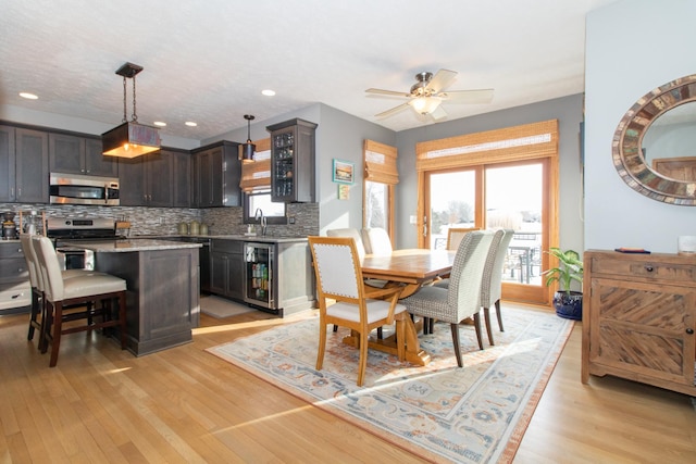 dining space featuring light wood finished floors, wine cooler, and a wealth of natural light