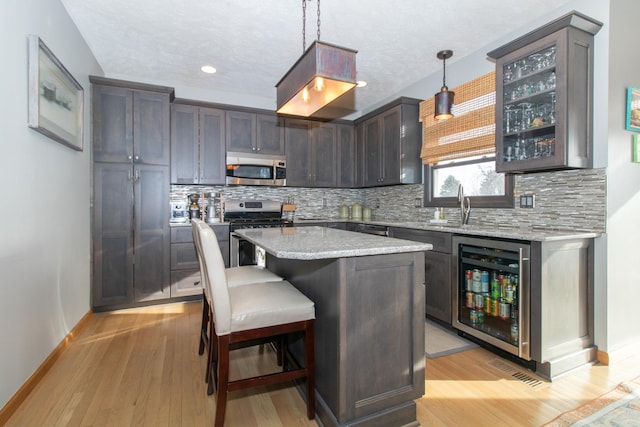 kitchen with decorative backsplash, wine cooler, appliances with stainless steel finishes, and a sink