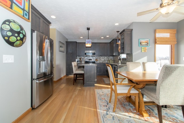 dining space with ceiling fan, baseboards, light wood-type flooring, recessed lighting, and a textured ceiling