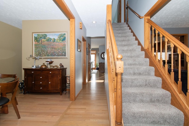 staircase featuring a textured ceiling and wood finished floors