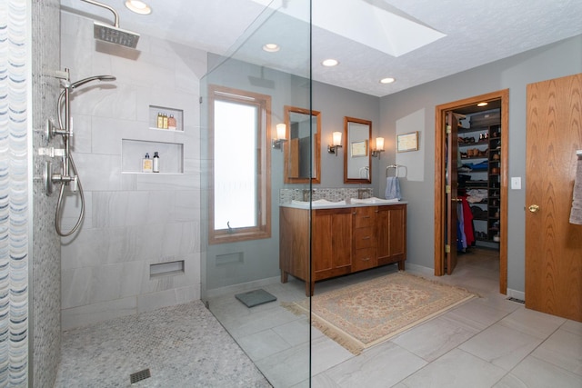 bathroom with visible vents, a walk in shower, a walk in closet, a skylight, and vanity