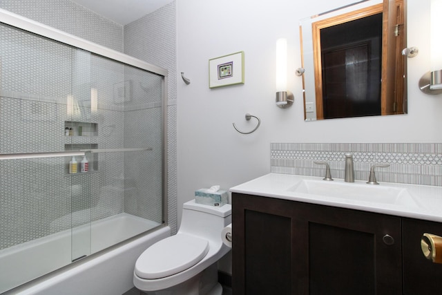 bathroom featuring backsplash, toilet, vanity, and bath / shower combo with glass door