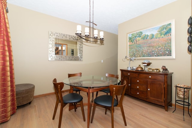 dining area featuring a chandelier, light wood-style flooring, and baseboards