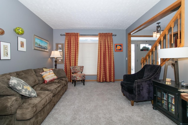 living room with stairs, carpet floors, and a textured ceiling