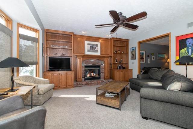 living room featuring light colored carpet, a brick fireplace, a ceiling fan, and a textured ceiling