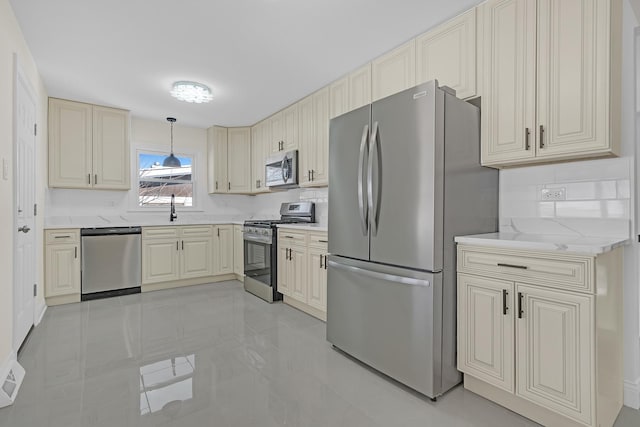 kitchen with sink, appliances with stainless steel finishes, backsplash, hanging light fixtures, and light stone countertops