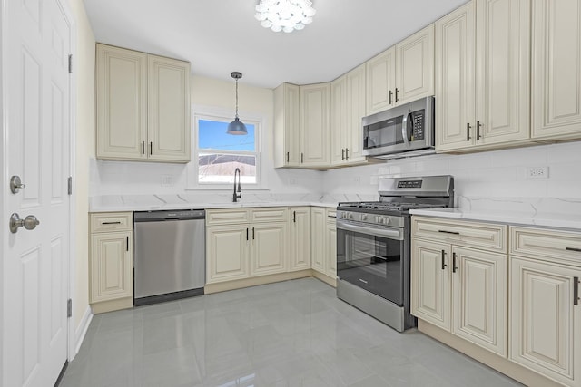 kitchen featuring sink, appliances with stainless steel finishes, hanging light fixtures, cream cabinets, and light stone countertops