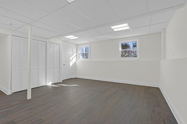 basement featuring a paneled ceiling and dark hardwood / wood-style floors