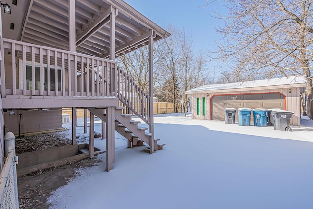 snowy yard featuring a garage and an outbuilding