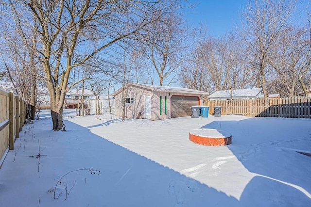 snowy yard featuring a storage unit and a garage