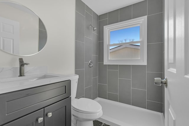 bathroom with vanity, toilet, and a tile shower