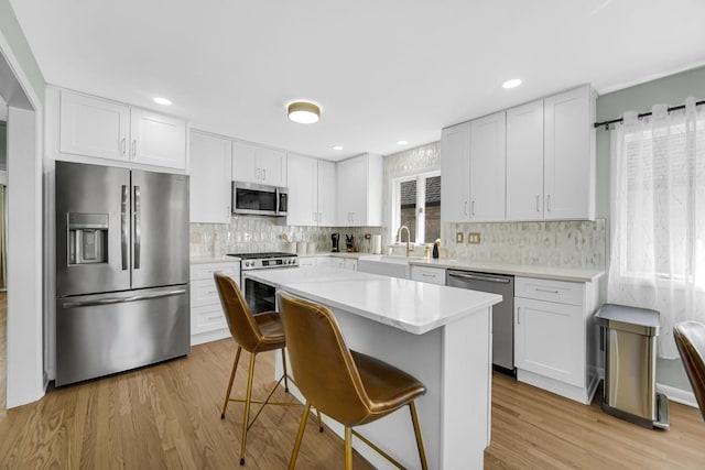 kitchen with white cabinetry, appliances with stainless steel finishes, a kitchen breakfast bar, and a center island