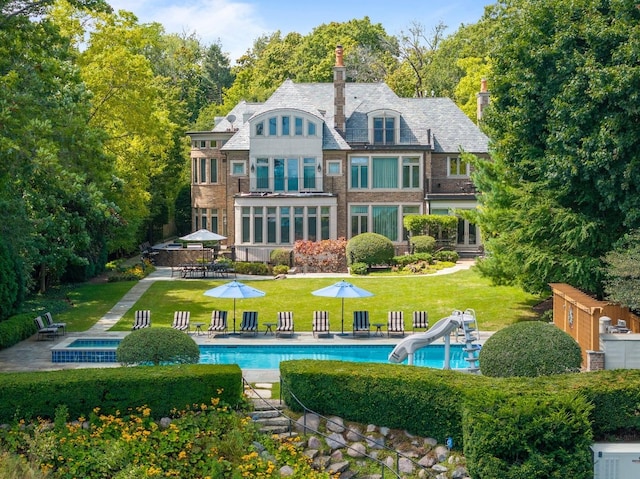 back of property featuring an outdoor pool, a lawn, and a patio