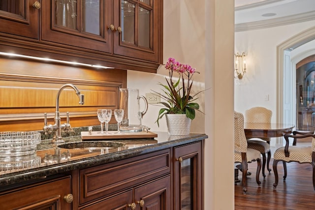 bar with beverage cooler, dark wood-type flooring, a sink, crown molding, and indoor wet bar