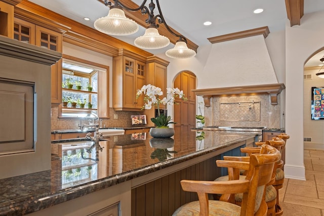 bar with stone tile floors, baseboards, decorative backsplash, hanging light fixtures, and custom exhaust hood