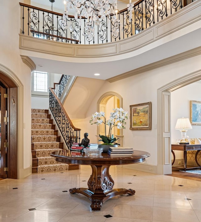 tiled entryway featuring stairway, a towering ceiling, and baseboards