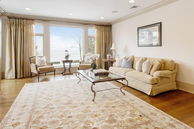 living area with recessed lighting, wood finished floors, visible vents, and crown molding